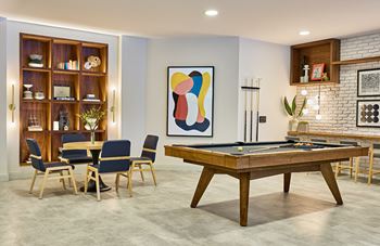 A living room with a pool table and a dining table